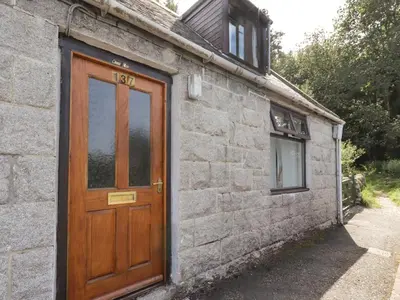 a wooden door on the side of a stone building at Wood End in Dalbeattie