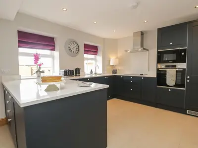 a kitchen with black cabinets and a clock on the wall at Carrock Cottage in Dalston