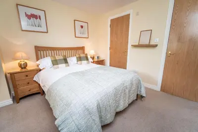 a bedroom with a bed and a night stand with a lamp at 11 Howrah's Court in Keswick