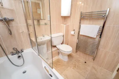 a bathroom with a toilet and a glass shower at 11 Howrah's Court in Keswick