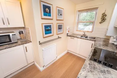 a kitchen with white cabinets and a sink at 11 Howrah's Court in Keswick