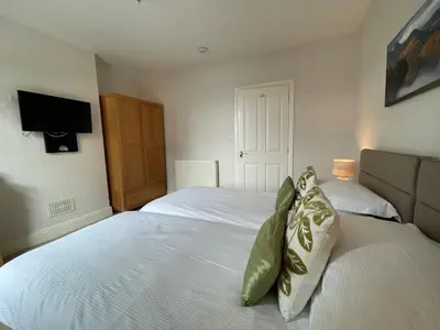 a bedroom with two beds and a tv on the wall at Abacourt Cottage in Keswick
