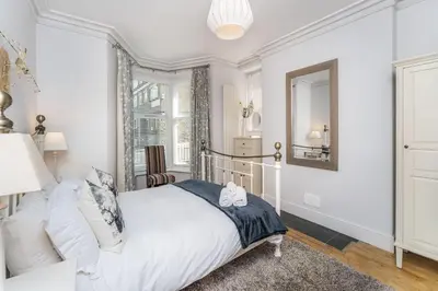 a white bedroom with a bed and a mirror at 3 The Townhouse in Keswick