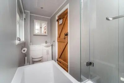 a bathroom with a shower and a toilet and a sink at Acorn Cottage in Keswick