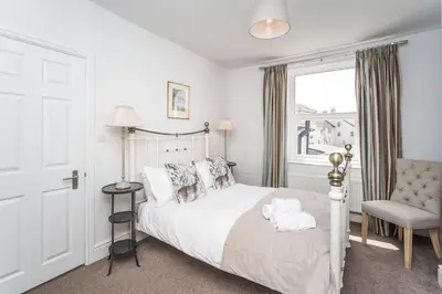 a bedroom with a bed and a chair and a window at 9 The Townhouse in Keswick