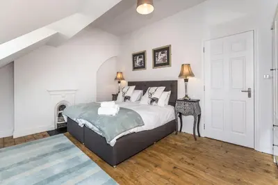 a white bedroom with a bed and a fireplace at 7 The Townhouse in Keswick