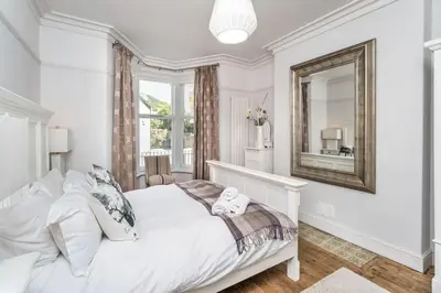 a white bedroom with a bed and a mirror at 7 The Townhouse in Keswick
