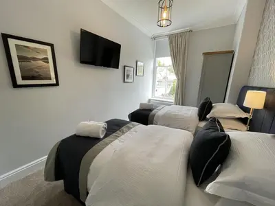 a room with three beds and a tv on the wall at Park View in Keswick