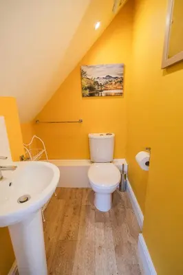 a yellow bathroom with a toilet and a sink at Skiddaw Skies in Keswick