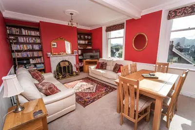 a living room with red walls and a couch and a table at Skiddaw Skies in Keswick