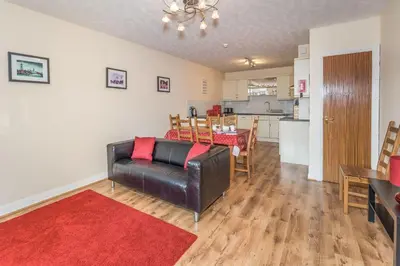 a living room with a couch and a table and a kitchen at Alban Rise in Keswick