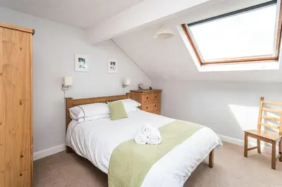 a bedroom with a bed and a window and a chair at Alban Rise in Keswick