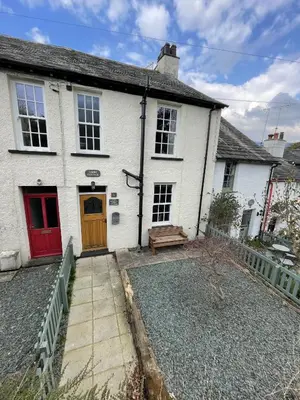 a white house with a red door and a bench at Tawny Cottage in Portinscale