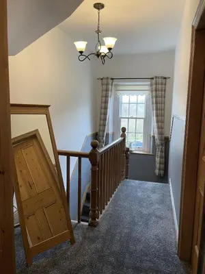 a room with a staircase with a window and a chandelier at Tawny Cottage in Portinscale