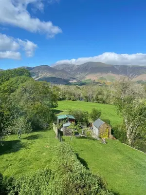 a house in a field with mountains in the background at Roslin in Portinscale