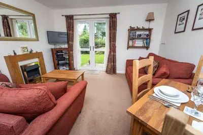 a living room with two couches and a table at Quaver Cottage in Keswick
