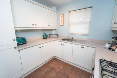 a kitchen with white cabinets and a sink at Elm Cottage in Keswick