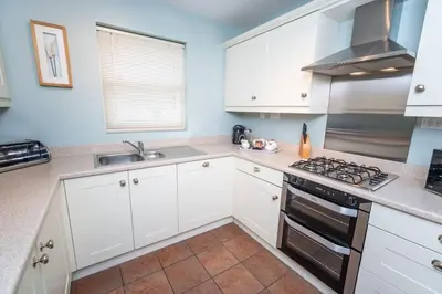 a kitchen with white cabinets and a stove top oven at Elm Cottage in Keswick