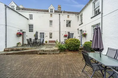 a patio with a table and chairs and a building at Bridge House in Keswick