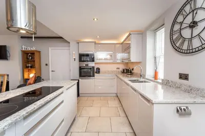 a kitchen with white cabinets and a large clock on the wall at Bridge House Apartment 1 in Keswick