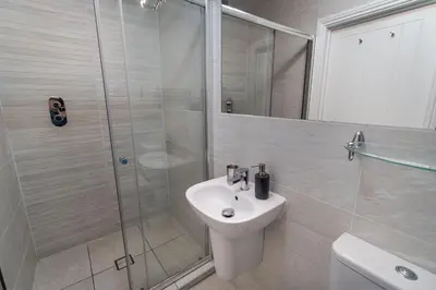 a white bathroom with a shower and a sink at Bridge House Apartment 1 in Keswick