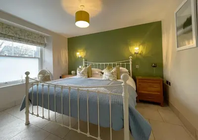 a bedroom with a bed and a green wall at Bridge House Apartment 1 in Keswick