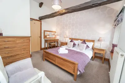 a bedroom with a bed and a dresser and a chair at Bridge House Apartment 3 in Keswick