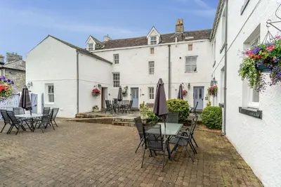 a patio with tables and chairs in front of a building at Bridge House Apartment 3 in Keswick