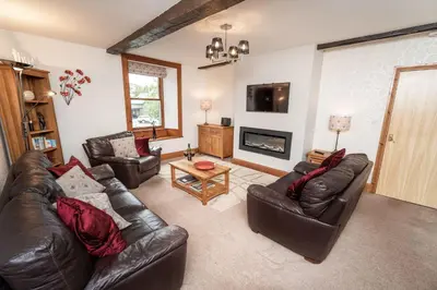 a living room with leather furniture and a fireplace at Bridge House Apartment 2 in Keswick