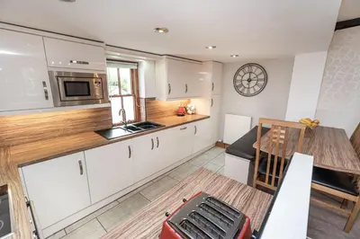 a kitchen with white cabinets and a wooden table at Bridge House Apartment 2 in Keswick
