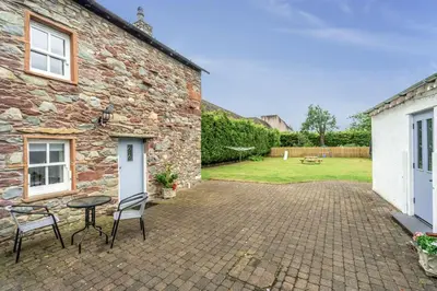 a patio with a table and chairs in front of a brick building at Bridge Mews in Keswick