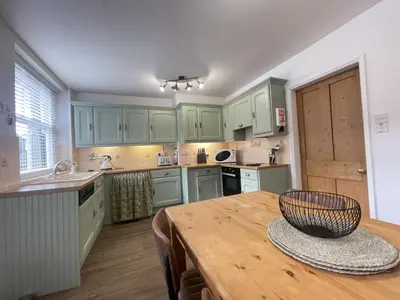 a kitchen with green cabinets and a wooden table at Birchgate in Keswick