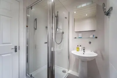 a white bathroom with a shower and a sink at Maiden Moor in Keswick