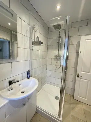 a white bathroom with a shower and a sink at Lake View Cottage in Braithwaite