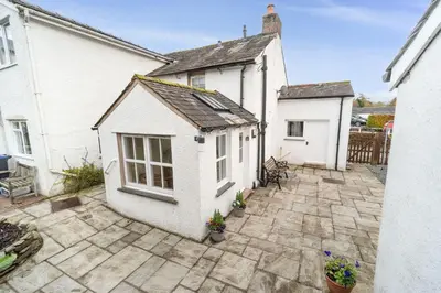 a white house with a patio in front of it at Jasmine Cottage in Portinscale