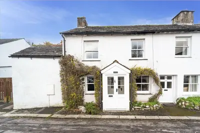 a white house with a white door and ivy at Jasmine Cottage in Portinscale