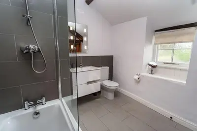 a bathroom with a tub and a toilet and a shower at Jasmine Cottage in Portinscale