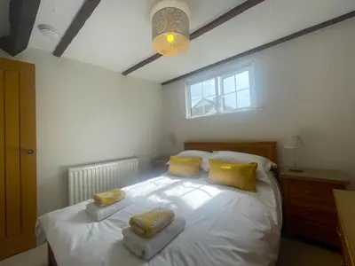 a bedroom with a large white bed with yellow pillows at Daisy Cottage in Keswick