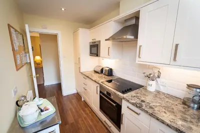 a kitchen with white cabinets and a counter top at Greta Bank in Keswick