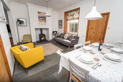 a living room with a dining table and yellow chairs at Coleridge Cottage in Keswick