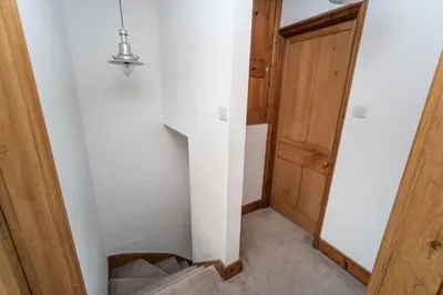 a hallway with a white wall and a stair case at Coleridge Cottage in Keswick