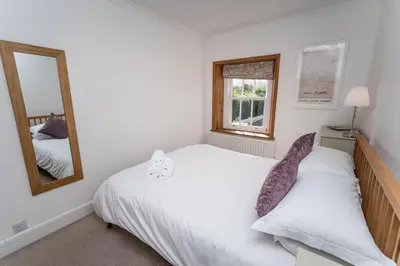 a bedroom with a white bed and a mirror at Coleridge Cottage in Keswick