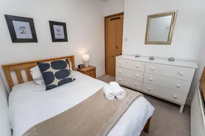 a bedroom with a bed and a dresser with a mirror at Coleridge Cottage in Keswick