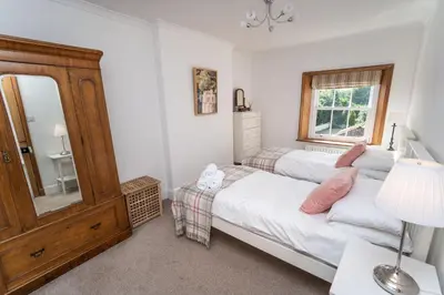 a bedroom with two beds and a mirror at Coleridge Cottage in Keswick