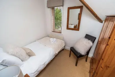 a bedroom with two beds and a mirror and a chair at Rose Bank Cottage in Braithwaite