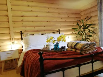 a bedroom with a bed with a wooden wall at Ravenglass Log Cabin in Ravenglass