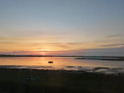 a boat in the water with the sunset in the background at Ravenglass Log Cabin in Ravenglass