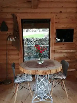 a table in a room with a vase of flowers on it at Ravenglass Log Cabin in Ravenglass