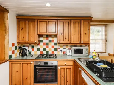 a kitchen with wooden cabinets and a stove top oven at 2 Burnside Place in Kirkcudbright