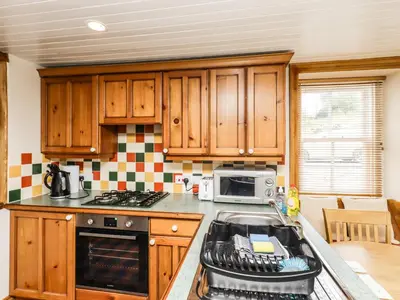 a kitchen with wooden cabinets and a stove top oven at 2 Burnside Place in Kirkcudbright